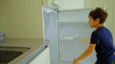 Little boy opens the refrigerator and takes an apple, a hungry child Stock Footage 219935924