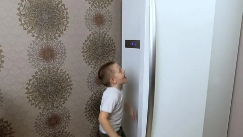 A little boy opens the refrigerator in the kitchen and chooses for a long time Stock Footage 167650492