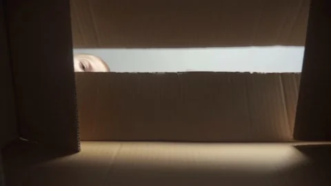 Little boy opens a surprise parcel. kid opens a cardboard box looking gift Stock Footage 136446218