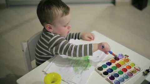 Little boy paints paints on table Stock Footage 73360037