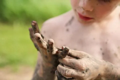 Little Boy Picking Mud off his Dirty Hands Stock Photos