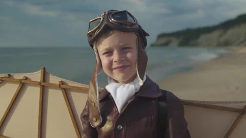 Little boy in pilot suit with artificial wings on his back stands on seashore 스톡 동영상 279898528