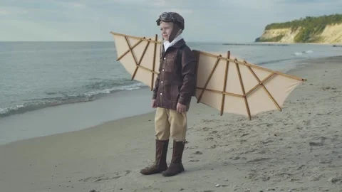 Little boy in pilot suit with artificial wings on his back stands on seashore. Stock-Footage 279898590