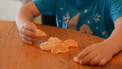 A little boy is playing and counting orange slices. hands close-up. Stock Footage 83459929