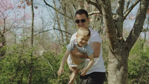 Little boy playing and having fun with his father in a park on a sunny day Stock-Footage 123443232