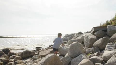 Little boy playing on big rocks near ocean Stock Footage 52954491