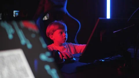 A little boy is playing computer games in a computer club in the dark. 스톡 동영상 330869526