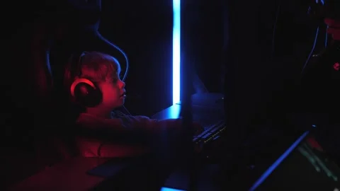 A little boy is playing computer games in a modern computer club in the dark. Stock Footage 332411137
