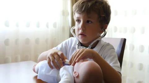 Little boy playing doctors with doll role playing medicine career future 4k Video stock 56582909