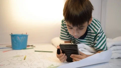 Little boy playing game on mobile with smile in the room Stockbeeldmateriaal 74616954