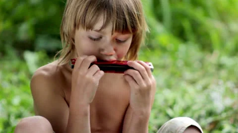 Little boy playing the harmonica Stock Footage 25672893
