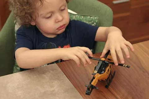 Little boy playing with helicopter on table. Developmental games. Transportation Stock Photos