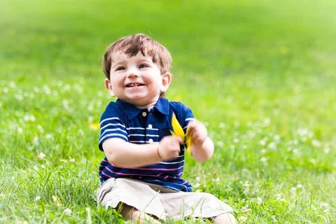 Little boy playing with a leaf in the grass Stock Photos