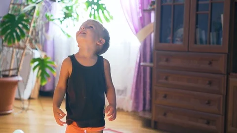 Little boy playing with a lot of multicolored baloons, slow motion. Indoor Stock Footage 107840459