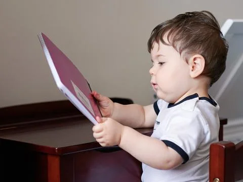Little boy playing with a notebook at a mini desk Stock-Fotos