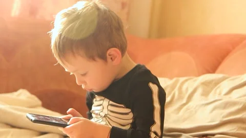 Little boy playing on the phone while sitting on the sofa Video stock 268628930