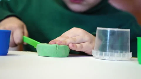 Little boy is playing plasticine sitting at the table. hands closeup Stock Footage 85771462