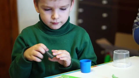 Little boy is playing plasticine sitting at the table. close-up portrait Stock Footage 85771877