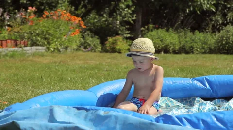 Little boy playing in a pool in the garden Stock Footage 65839615