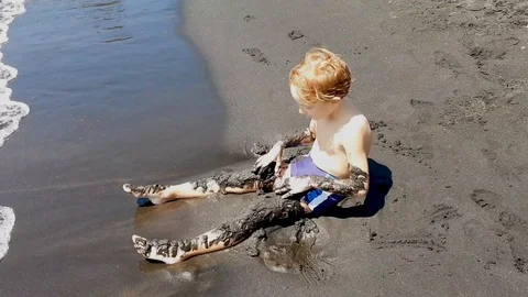 Little boy playing with sand on the beach Stock Footage 115323599