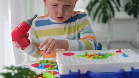Little boy playing set with a screwdriver and a drill,  and screws and parts . Stock Footage 173521394