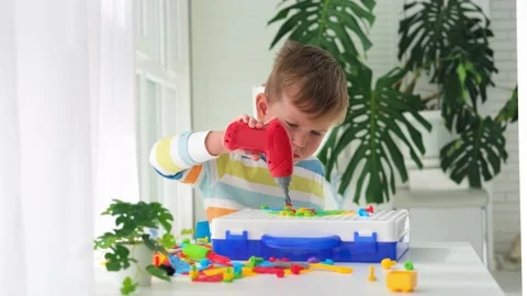 Little boy playing set with a screwdriver and a drill,  and screws and parts . Stock Footage 227944279