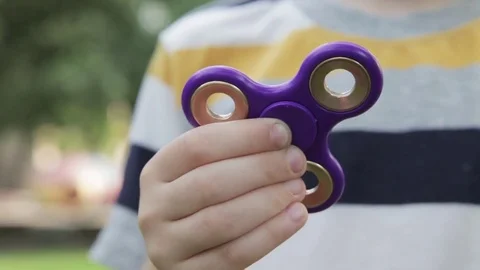 A little boy is playing with a spinner. The boy is spinning a spinner in his Stock Footage 77592374