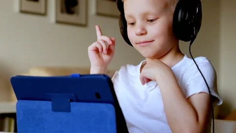 Little boy Playing with Tablet PC wearing headphones Stock Footage 90367631