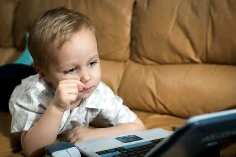 Little boy is playing on the teaching computer at home on the couch Foto stock
