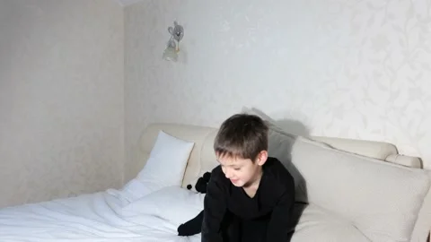 Little boy playing with a teddy bear in white bed Stock Footage 151973643