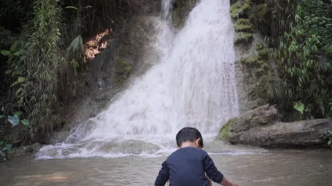 Little boy playing waterfall pool in deep forest Stock Footage 145199427