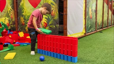 Little boy plays big constructor in mall. Kid builds multi-colored lego tower in Video stock 255672627