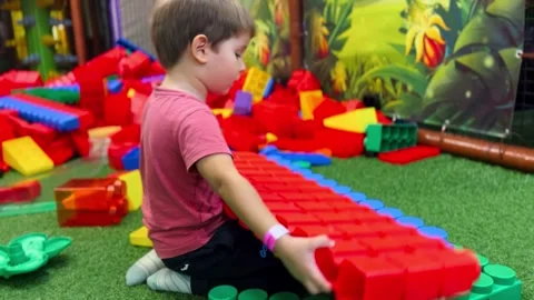 Little boy plays big constructor in mall. Kid builds multi-colored tower in Video stock 255799168
