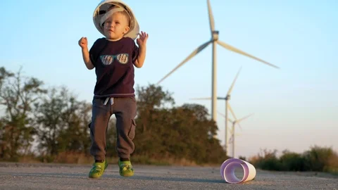 A little boy plays with constructor helmet. He puts it on and jumps until it Video stock 96837672