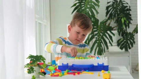 A little boy plays a set with a screwdriver and a drill, screws and parts. Stock Footage 227944396