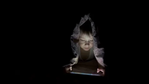 Little boy plays on tablet while lying under blanket. watching cartoons hiding Stock-Footage 125927219