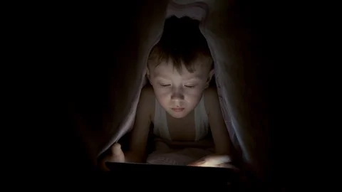 Little boy plays on tablet while lying under blanket. watching cartoons hiding Stock-Footage 125927230