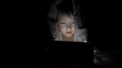 Little boy plays on tablet while lying under blanket. watching cartoons hiding Stock-Footage 125927231
