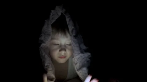 Little boy plays on tablet while lying under blanket. watching cartoons hiding Stock-Footage 125927239