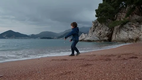 Little boy plays with waves on seashore outdoors. Video stock 76507377