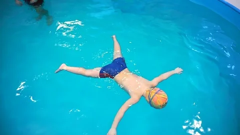A little boy in the pool, the coach teaches him to swim, top view. The boy holds Video stock 101497835