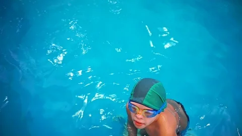 A little boy in the pool learning to swim, top view, he jumps into the water. 스톡 동영상 101497742