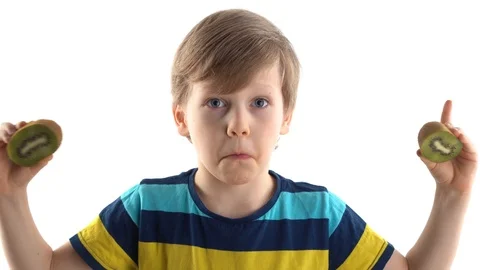 Little boy posing in studio on a white background with cut kiwi instead of eyes Stock Footage 124458847