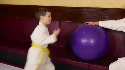 A little boy practices a circular kick on a ball held by a trainer Stock Footage 268707860