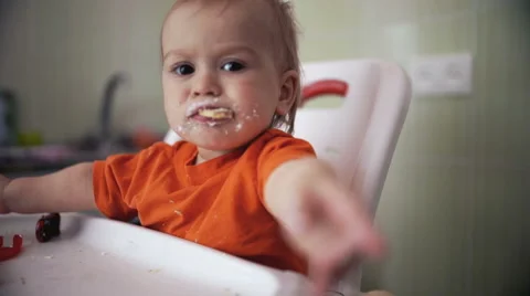 Little boy practices eating in the kitchen extends a hand 22  - Color corrected Stock Footage 55109876