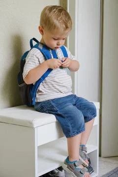 Little boy putting on backpack Stock Photos