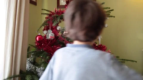 Little boy putting some decorations on Christmas tree Stock Footage 69784259