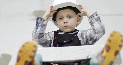 Little boy putting on a white builder helmet. Stock Footage 143696566
