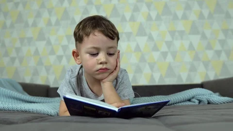 Little boy reading a book in bed Stock Footage 128974555