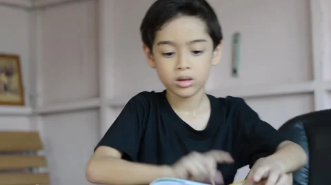 Little boy reading book on table at home Stockbeeldmateriaal 47703951